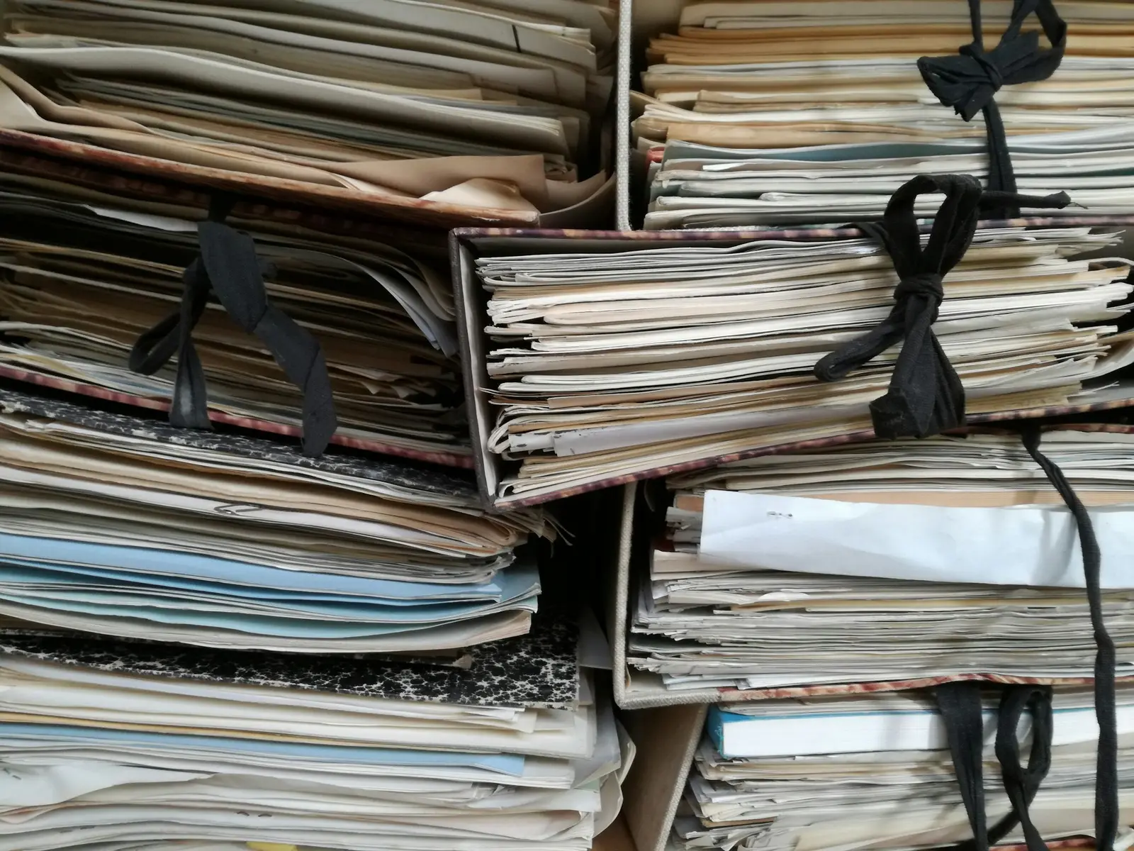 Autos de processos em papel amarrados com fita e empilhados em arquivo