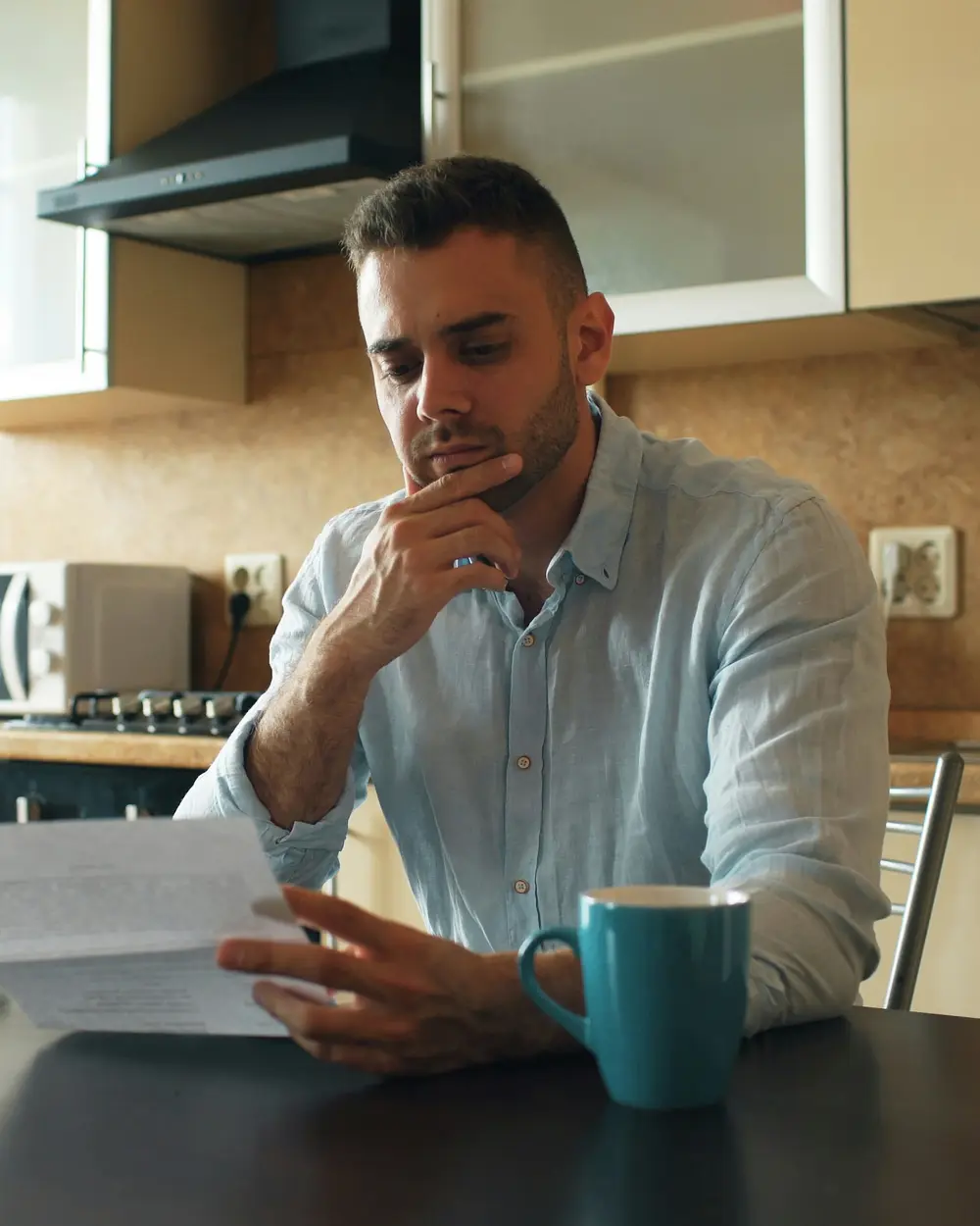 Homem lendo uma carta na mesa da cozinha